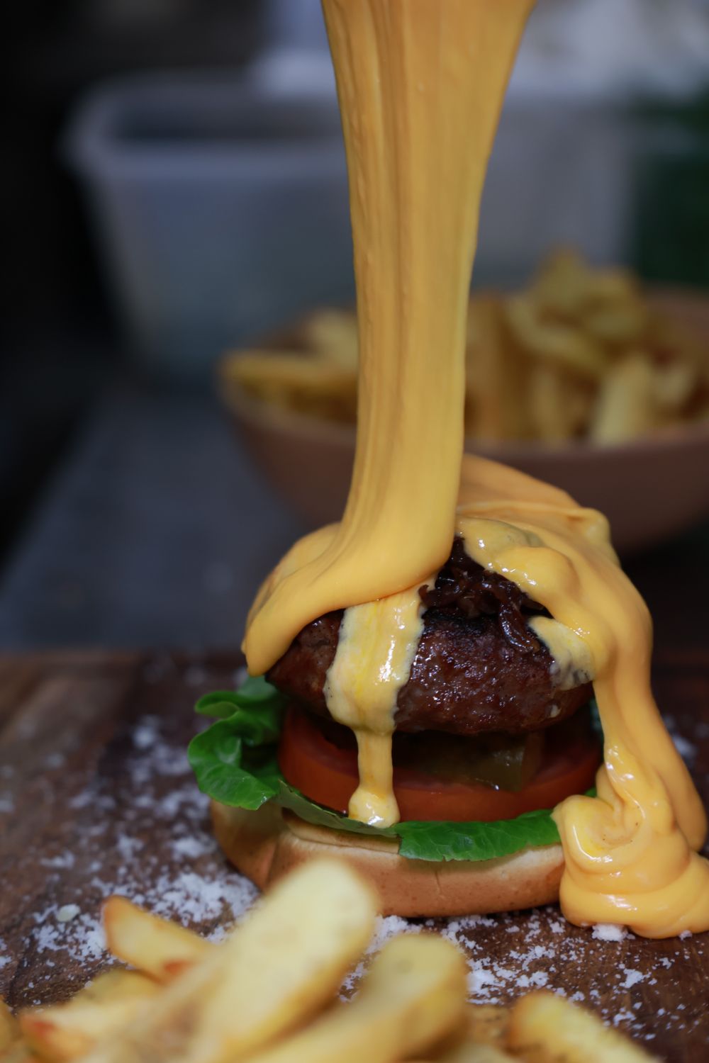 Melted cheese poured over a burger with fries at Terrazza